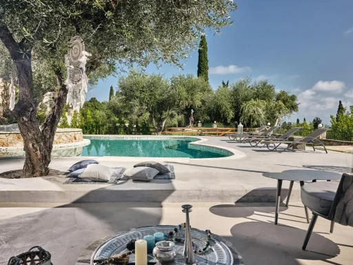 A serene outdoor space featuring a pool, olive trees, and sun loungers.